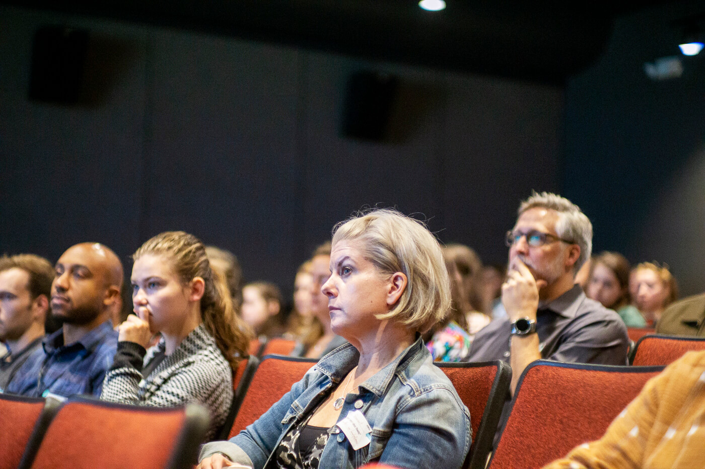 A crowd sitting in a theatre listens closely to what they're watching.